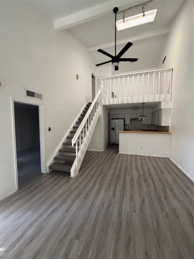 6347 Cattails Ln Unit 63, Houston, TX 77035 - unfurnished living room featuring ceiling fan, stairs, beamed ceiling, wood finished floors, and high vaulted ceiling