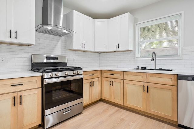 153 E Rittenhouse St, Houston, TX 77076 - kitchen with appliances with stainless steel finishes, wall chimney exhaust hood, light brown cabinets, light countertops, and light wood-style flooring