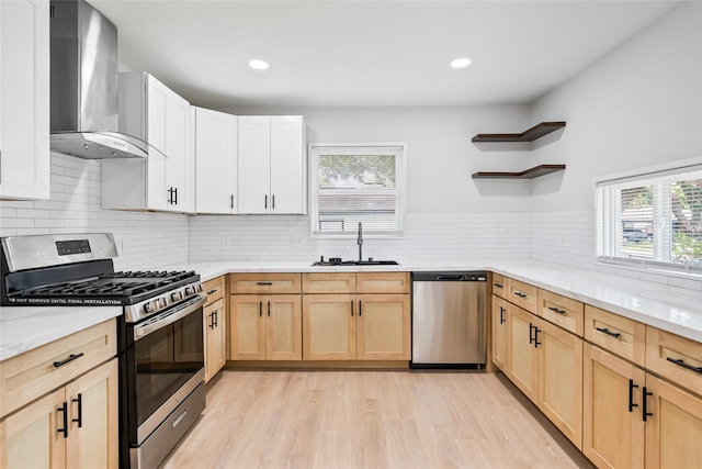 153 E Rittenhouse St, Houston, TX 77076 - kitchen featuring appliances with stainless steel finishes, wall chimney range hood, light brown cabinetry, open shelves, and healthy amount of natural light