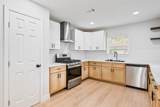153 E Rittenhouse St, Houston, TX 77076 - kitchen with stainless steel appliances, wall chimney exhaust hood, open shelves, light countertops, and light brown cabinetry