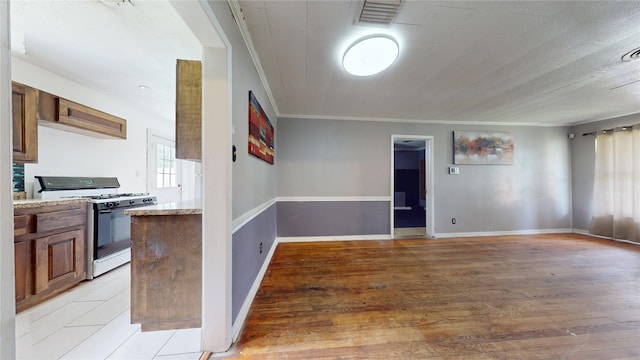 907 Axilda St, Houston, TX 77017 - kitchen featuring gas range gas stove, ornamental molding, light wood-style flooring, open floor plan, and brown cabinets
