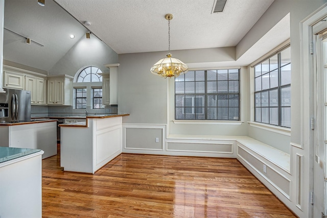 4417 Alamance St, Baytown, TX 77521 - kitchen with stainless steel fridge with ice dispenser, light wood finished floors, a chandelier, a textured ceiling, and wainscoting