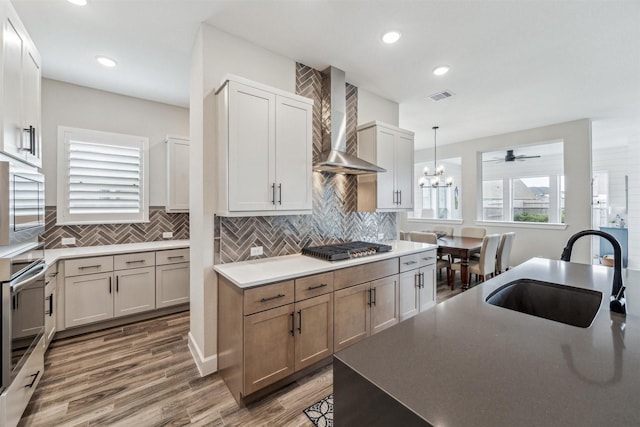 2802 Tarragon Crest Dr, Katy, TX 77494 - kitchen with wall chimney exhaust hood, stainless steel appliances, tasteful backsplash, a chandelier, and wood finished floors