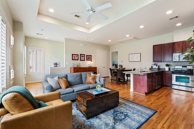 3908 Center St, Houston, TX 77007 - living room with light wood-type flooring, a ceiling fan, a tray ceiling, and recessed lighting