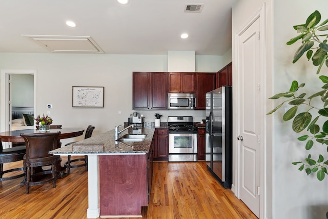 3908 Center St, Houston, TX 77007 - kitchen with appliances with stainless steel finishes, a peninsula, dark stone countertops, light wood-style floors, and recessed lighting