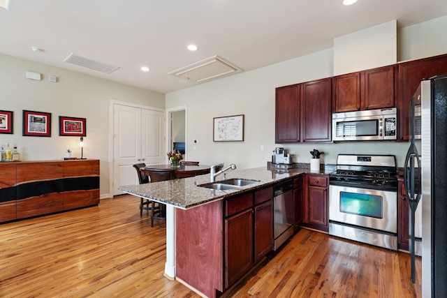 3908 Center St, Houston, TX 77007 - kitchen with appliances with stainless steel finishes, a peninsula, light wood finished floors, dark stone countertops, and recessed lighting