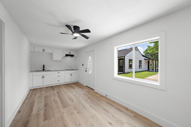 7711 Greenstone St, Houston, TX 77087 - kitchen featuring light wood-type flooring, white cabinets, ceiling fan, black electric cooktop, and a textured ceiling
