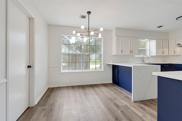 910 Woodchurch Ln, Houston, TX 77073 - kitchen with blue cabinets, light wood-type flooring, healthy amount of natural light, wainscoting, and a textured ceiling