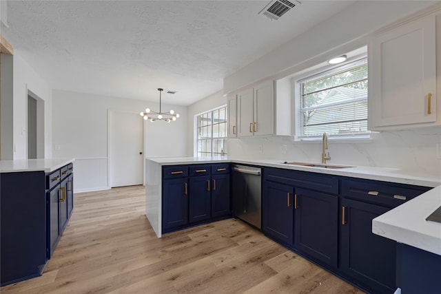 910 Woodchurch Ln, Houston, TX 77073 - kitchen with blue cabinets, dishwasher, a peninsula, a chandelier, and light countertops