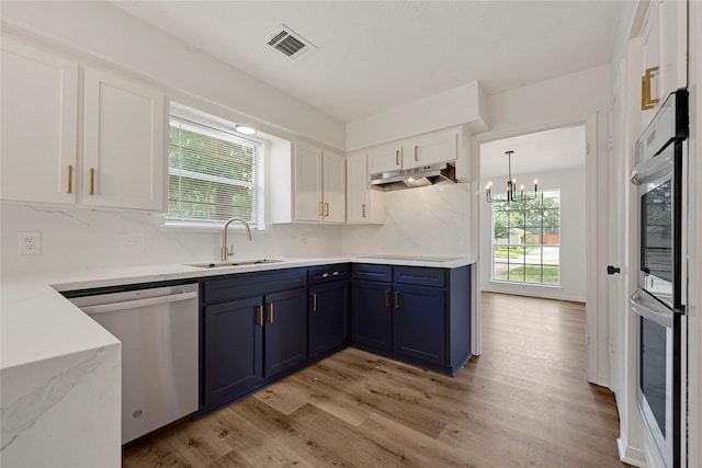 910 Woodchurch Ln, Houston, TX 77073 - kitchen featuring dishwashing machine, blue cabinetry, under cabinet range hood, white cabinetry, and light wood finished floors