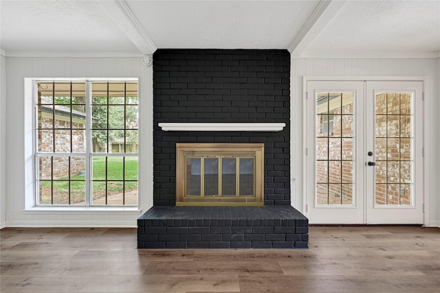 910 Woodchurch Ln, Houston, TX 77073 - unfurnished living room with beamed ceiling, a textured ceiling, a brick fireplace, wood finished floors, and french doors