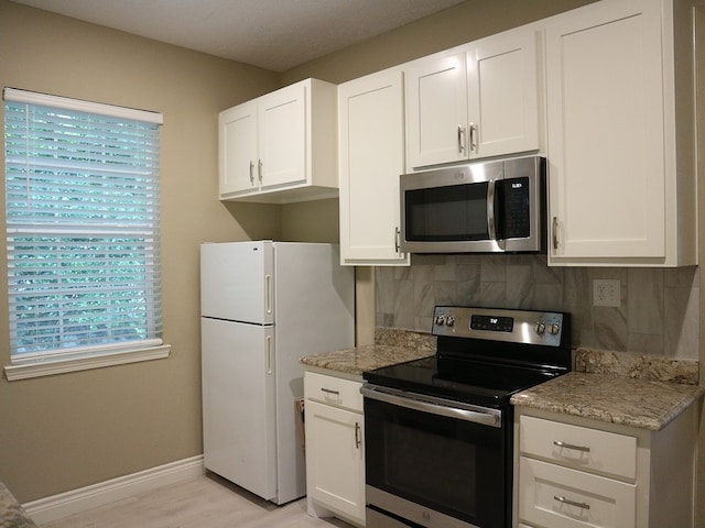 1306 S Austin St, Brenham, TX 77833 - kitchen featuring stainless steel appliances, decorative backsplash, white cabinetry, and light wood-style floors