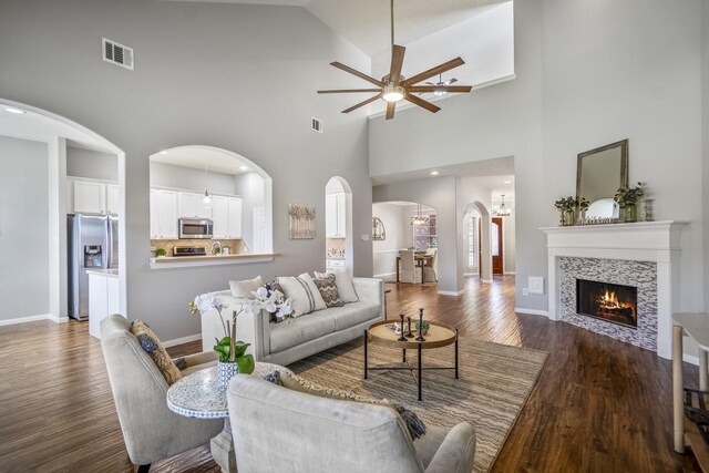 7214 Emerald Run Ln, Spring, TX 77379 - living area featuring a ceiling fan, arched walkways, dark wood finished floors, high vaulted ceiling, and a tiled fireplace