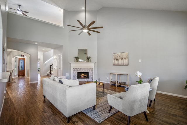 7214 Emerald Run Ln, Spring, TX 77379 - living room featuring ceiling fan, a tiled fireplace, arched walkways, stairs, and dark wood-style floors