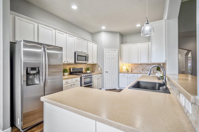 7214 Emerald Run Ln, Spring, TX 77379 - kitchen featuring stainless steel appliances, white cabinetry, tasteful backsplash, a peninsula, and pendant lighting