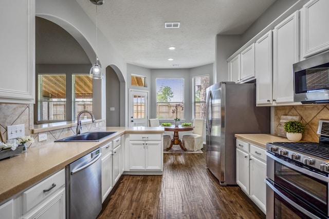 7214 Emerald Run Ln, Spring, TX 77379 - kitchen with appliances with stainless steel finishes, arched walkways, a peninsula, white cabinets, and a textured ceiling