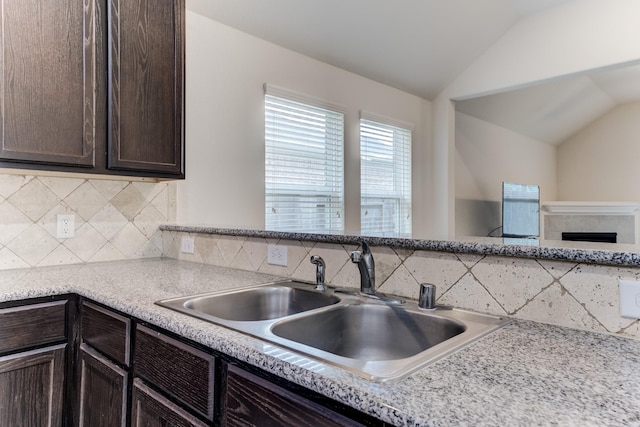 14726 Lark Sky Way, Cypress, TX 77429 - kitchen with vaulted ceiling, dark brown cabinetry, backsplash, light countertops, and a fireplace