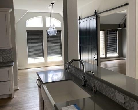 19007 Dappled Mare Cir, Tomball, TX 77377 - kitchen featuring vaulted ceiling, a barn door, dark countertops, wood finished floors, and pendant lighting