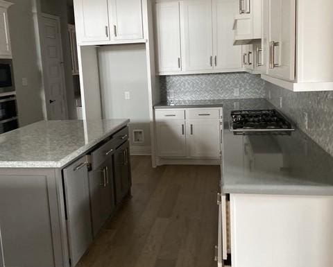 19007 Dappled Mare Cir, Tomball, TX 77377 - kitchen featuring stainless steel appliances, wood finished floors, a center island, white cabinetry, and decorative backsplash
