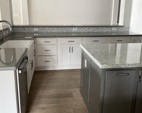19007 Dappled Mare Cir, Tomball, TX 77377 - kitchen with dark wood-style flooring, white cabinets, light stone countertops, stainless steel dishwasher, and a kitchen island