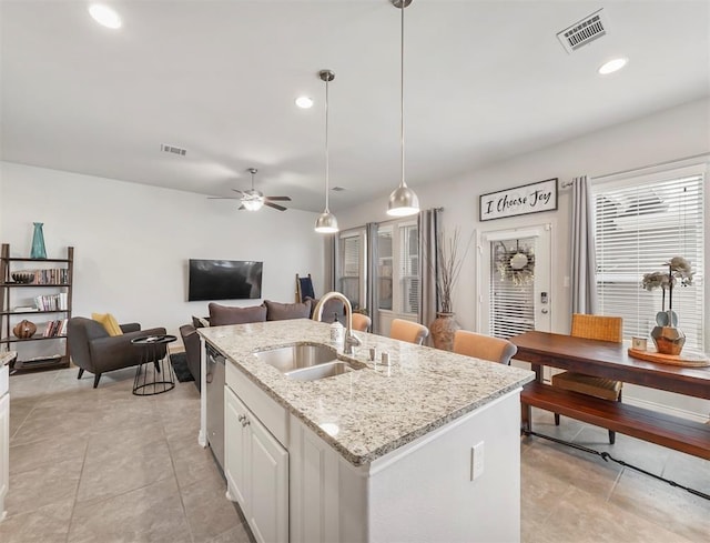 17023 Canosa Dr, Cypress, TX 77433 - kitchen with dishwasher, a ceiling fan, a kitchen island with sink, light stone counters, and light tile patterned floors
