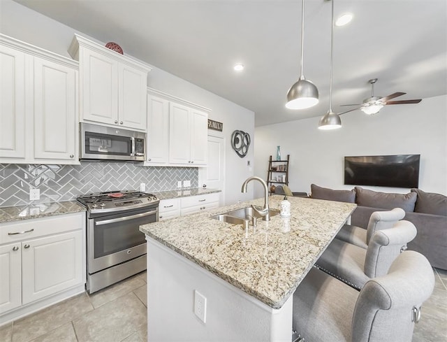 17023 Canosa Dr, Cypress, TX 77433 - kitchen featuring stainless steel appliances, tasteful backsplash, white cabinetry, open floor plan, and ceiling fan