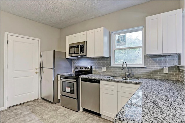4137 Galesburg St, Houston, TX 77051 - kitchen featuring stainless steel appliances, white cabinets, light stone counters, tasteful backsplash, and a textured ceiling