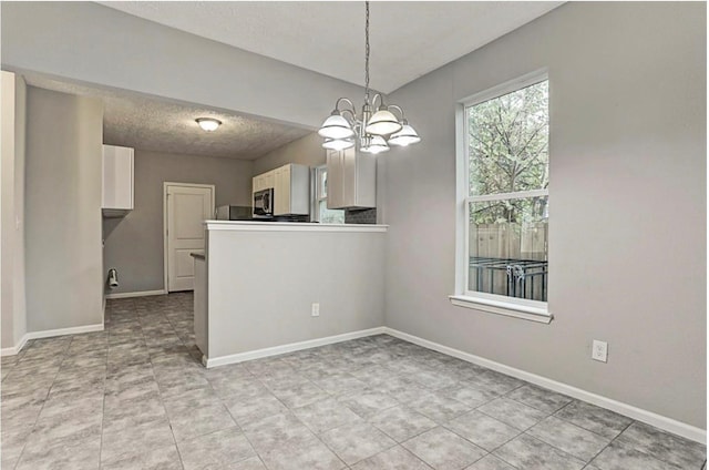 4137 Galesburg St, Houston, TX 77051 - kitchen with a chandelier, stainless steel microwave, white cabinetry, pendant lighting, and light tile patterned flooring