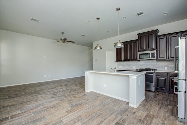 17019 Canosa Dr, Cypress, TX 77433 - kitchen featuring appliances with stainless steel finishes, ceiling fan, light countertops, backsplash, and light wood finished floors