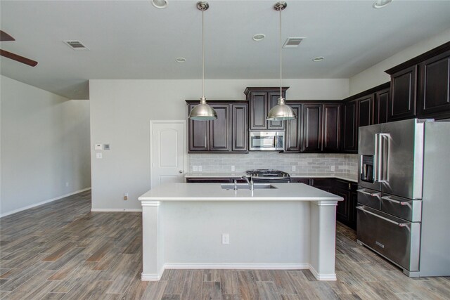 17019 Canosa Dr, Cypress, TX 77433 - kitchen featuring stainless steel appliances, light countertops, tasteful backsplash, light wood-style floors, and an island with sink