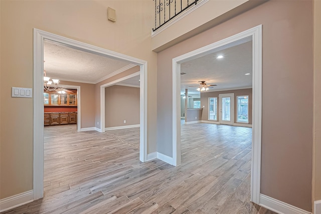 5942 Pebble Springs Dr, Houston, TX 77066 - corridor featuring ornamental molding, a chandelier, light wood-style floors, and a textured ceiling
