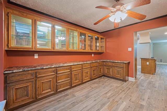 5942 Pebble Springs Dr, Houston, TX 77066 - kitchen with brown cabinets, light wood finished floors, glass insert cabinets, stone counters, and a textured ceiling