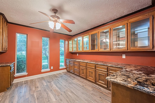 5942 Pebble Springs Dr, Houston, TX 77066 - kitchen with brown cabinets, a textured ceiling, light wood-style flooring, a ceiling fan, and glass insert cabinets