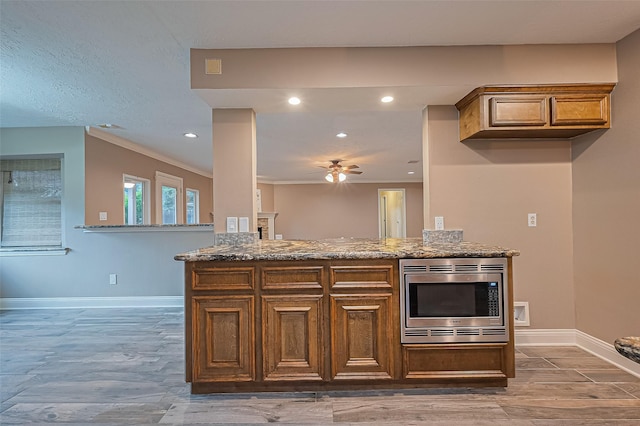 5942 Pebble Springs Dr, Houston, TX 77066 - kitchen with stainless steel microwave, ceiling fan, stone counters, ornamental molding, and recessed lighting
