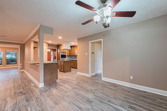5942 Pebble Springs Dr, Houston, TX 77066 - kitchen featuring stainless steel oven, light wood-type flooring, a ceiling fan, brown cabinetry, and custom exhaust hood
