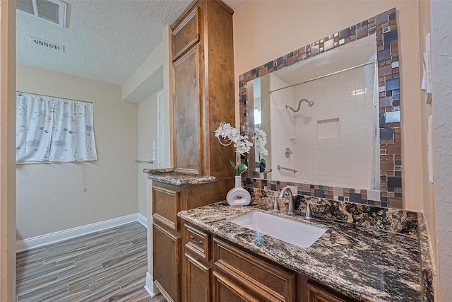 5942 Pebble Springs Dr, Houston, TX 77066 - bathroom with vanity, wood finished floors, a tile shower, and a textured ceiling