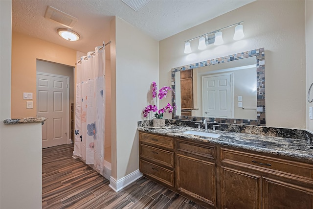 5942 Pebble Springs Dr, Houston, TX 77066 - full bathroom featuring wood finish floors, vanity, a textured ceiling, and a shower with shower curtain