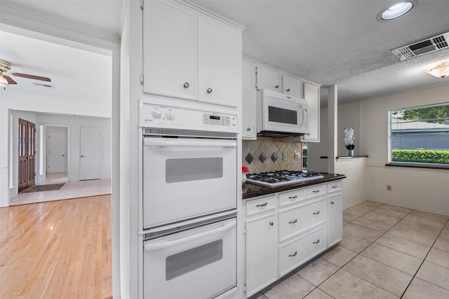 1403 Maygrove Dr, Sugar Land, TX 77498 - kitchen featuring white appliances, dark countertops, white cabinets, decorative backsplash, and a ceiling fan