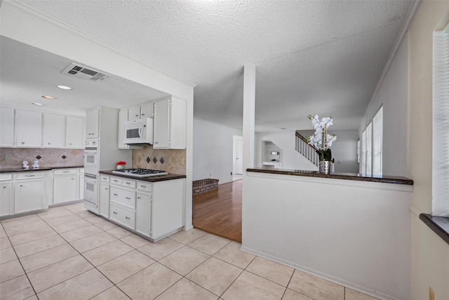 1403 Maygrove Dr, Sugar Land, TX 77498 - kitchen with white appliances, dark countertops, white cabinetry, light tile patterned flooring, and a textured ceiling