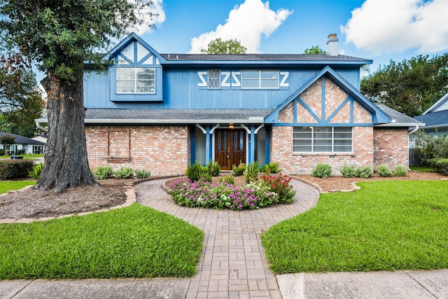 1403 Maygrove Dr, Sugar Land, TX 77498 - tudor house with brick siding, a front lawn, a shingled roof, and a chimney