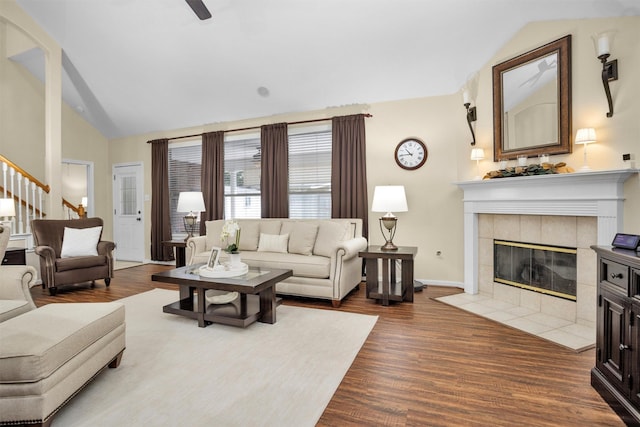 21006 Indigo Field Ln, Richmond, TX 77407 - living room with a tile fireplace, dark wood-style floors, stairs, a ceiling fan, and high vaulted ceiling