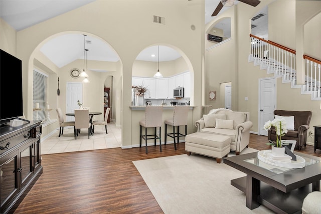 21006 Indigo Field Ln, Richmond, TX 77407 - living room with arched walkways, light wood finished floors, ceiling fan, stairway, and high vaulted ceiling