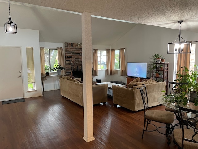 3202 The Highlands Dr, Sugar Land, TX 77478 - living area featuring vaulted ceiling, dark wood-type flooring, a brick fireplace, a chandelier, and a textured ceiling