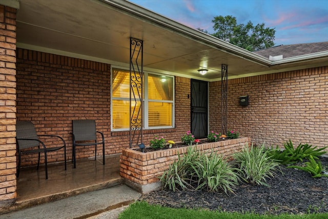 1130 W 30th St, Houston, TX 77018 - exterior entry at dusk featuring brick siding, covered porch, and a shingled roof