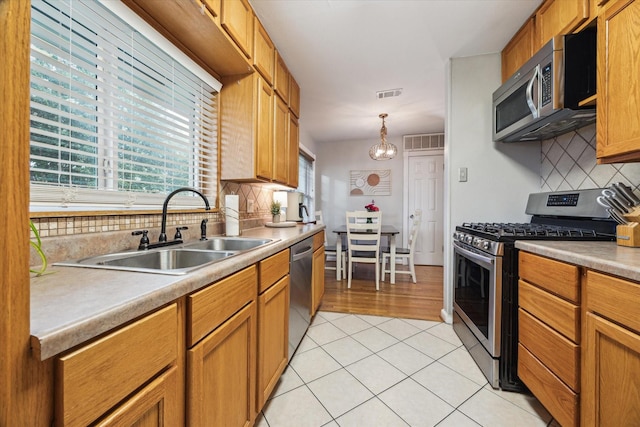 1130 W 30th St, Houston, TX 77018 - kitchen featuring appliances with stainless steel finishes, backsplash, light tile patterned flooring, light countertops, and pendant lighting