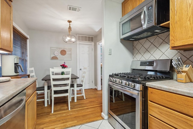 1130 W 30th St, Houston, TX 77018 - kitchen with appliances with stainless steel finishes, tasteful backsplash, a chandelier, light countertops, and pendant lighting