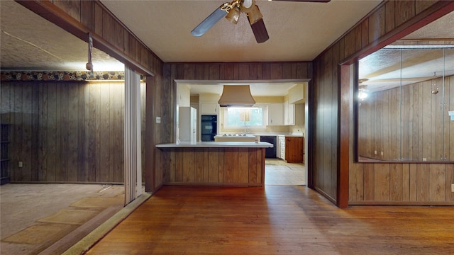 6619 Heron Dr, Houston, TX 77087 - kitchen with black appliances, premium range hood, wood walls, wood finished floors, and ceiling fan