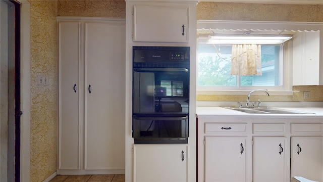 6619 Heron Dr, Houston, TX 77087 - kitchen featuring oven, a warming drawer, wallpapered walls, white cabinets, and light countertops
