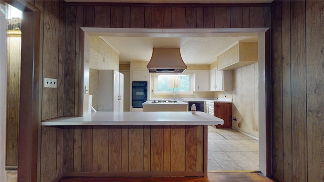 6619 Heron Dr, Houston, TX 77087 - kitchen with extractor fan, black oven, a peninsula, light countertops, and white cabinetry