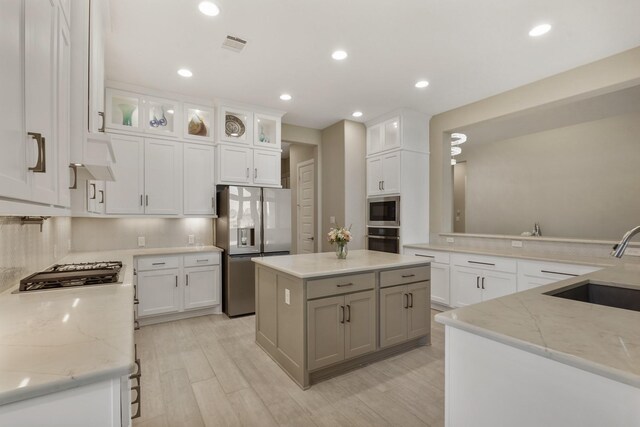 19019 Dappled Mare Cir, Tomball, TX 77377 - kitchen with appliances with stainless steel finishes, light stone counters, white cabinetry, a kitchen island, and glass insert cabinets